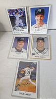 Five autographed baseball cards in sleeves showing player images and signatures