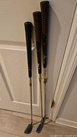 Three golf irons leaning against door
