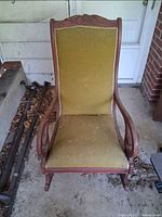 Front view of high-back rocking chair showing upholstery and carved crest