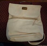 Front view showing flap, zipper pocket, and logo plate