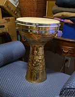 Full view of brass darbuka on chair