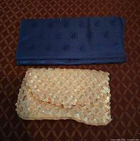 Front view of navy travel wallet and peach sequin clutch
