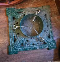 Top view of green cast iron Christmas tree stand showing square base and trunk sleeve