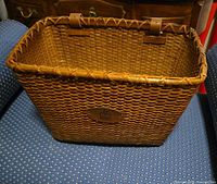 Front view of wicker bicycle basket showing overall shape, weave, and leather mounting straps