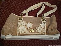 Front view of jute shoulder bag with PU trim, floral appliqué, and gold-tone hardware