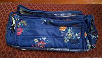 Front view showing navy floral exterior, zip compartments, Lug logo patch
