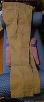 Full view of khaki pants laid flat showing overall condition and leg cut