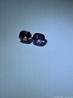 Two cushion-cut spinel gems on light background