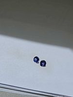 Pair of round blue-violet faceted stones on light background