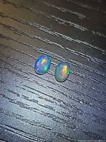 Two small oval opals with multicolour flash on dark surface