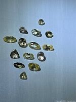 Group of 14 yellow faceted Tanzanite stones on blue background