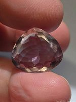 Faceted pear-cut amethyst held between fingers