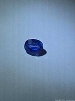 Top view of loose oval blue sapphire on white background