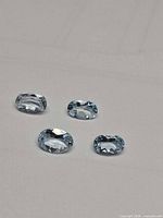 Four oval aquamarine gemstones on neutral background