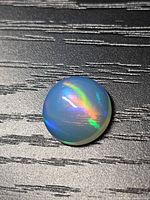 Top view of the round cabochon jelly opal showing play of colour