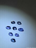Group of eight oval Tanzanite stones on neutral background