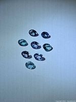 Eight faceted tanzanite stones arranged on white background