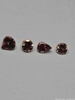 Four champagne tanzanite gemstones aligned on grey surface