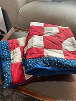 Two folded red, cream and blue quilted pillow shams on table