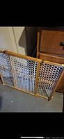 Front view of adjustable wood and plastic baby gate showing frame and mesh panel