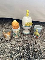Five egg cups arranged side by side showing designs and stone egg
