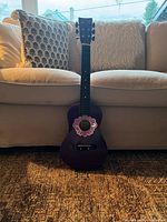 Full view of purple child acoustic guitar against sofa