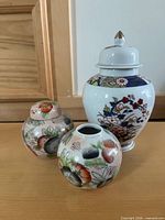Front view of three porcelain ginger jars showing size and lid presence