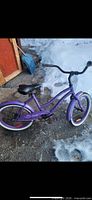Full view of purple 20" cruiser bicycle on ground showing frame, wheels, handlebars, saddle
