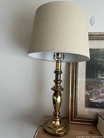 Full view of brass table lamp with shade on wooden surface