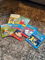 All eight French Pokémon books laid out on carpet showing covers and titles