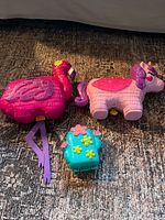 Flamingo, unicorn, and cactus Polly Pocket compacts on floor