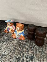 Two ceramic bear shakers and two wooden shakers displayed side by side