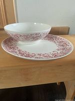 Serving bowl nested on platter showing red floral pattern