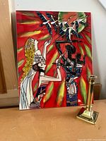 Overall view of ceramic tile artwork standing upright beside brass candlestick