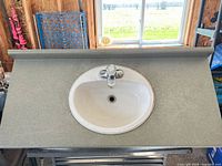 Top view of vanity top showing gray laminate surface, white oval sink, chrome faucet, and backsplash