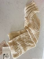 Full view of cream and beige lace knit alpaca scarf laid flat