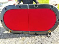Front view of unfolded oval poker table showing red felt and cup holders