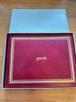 Guest book in slipcase showing red cover, gold trim and title