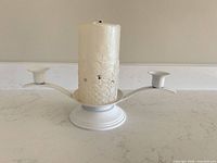 Front view of white metal candelabra with pillar candle