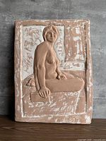 Front view of ceramic relief wall plaque showing seated female figure and overall surface