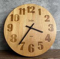 Front view showing wood face, carved numerals, hands, brand