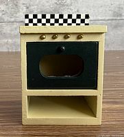 Front view of cream wooden stove/oven with gold knobs and checker backsplash