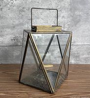 Front view of brass and glass geometric lantern showing handle and frame