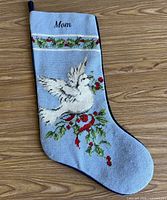 Front of stocking showing dove and holly needlepoint design with Mom personalization