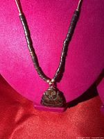 Close-up of stone Buddha pendant and surrounding dark beads