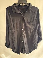 Front view of black button-up shirt on hanger