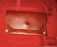 Front view closed brown leather wallet with button stud