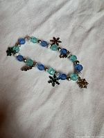 Full view of blue and teal glass bead stretch bracelet showing charms and bead pattern