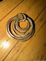 Front view of pendant showing seven interlocking hammered rings in brass and silver-tone metal