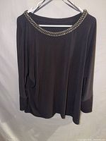 Full front view of black blouse on hanger
